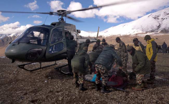 Photograph released by the Nepal Army on October 15, 2014, an injured survivor of a snow storm is assisted by army personel into a Nepalese Army helicopter in Manang District.  Photo Nepal Army