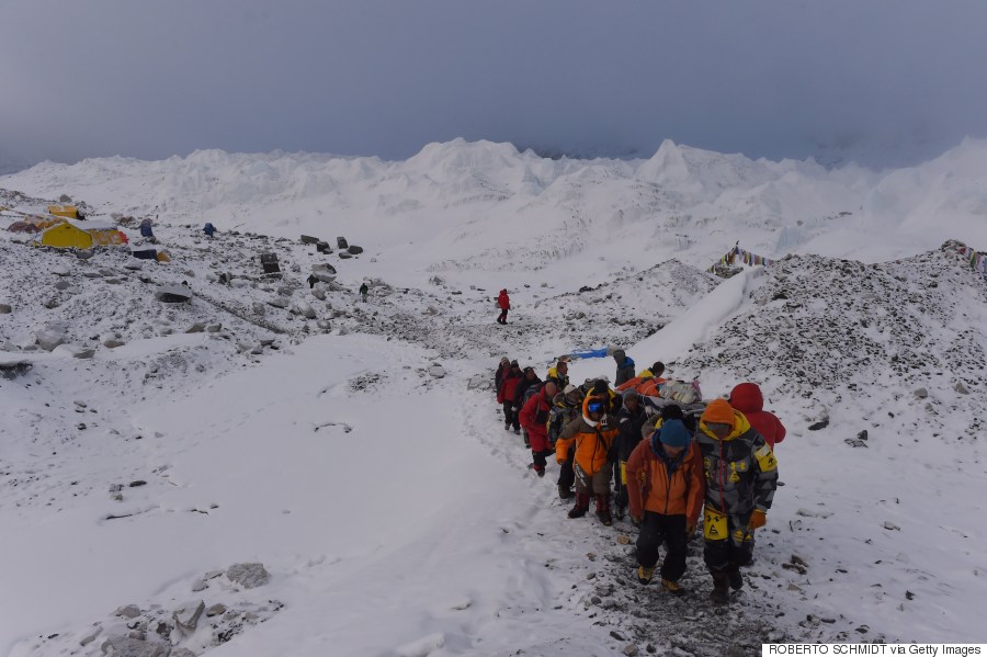 An injured person is carried by rescue members to be airlifted by rescue helicopter at Everest Base Camp on April 26, 2015, a day after an avalanche triggered by an earthquake devastated the camp. Rescuers in Nepal are searching frantically for survivors of a huge quake on April 25, that killed nearly 2,000, digging through rubble in the devastated capital Kathmandu and airlifting victims of an avalanche at Everest base Camp. The bodies of those who perished lie under orange tents. AFP PHOTO/ROBERTO SCHMIDT      