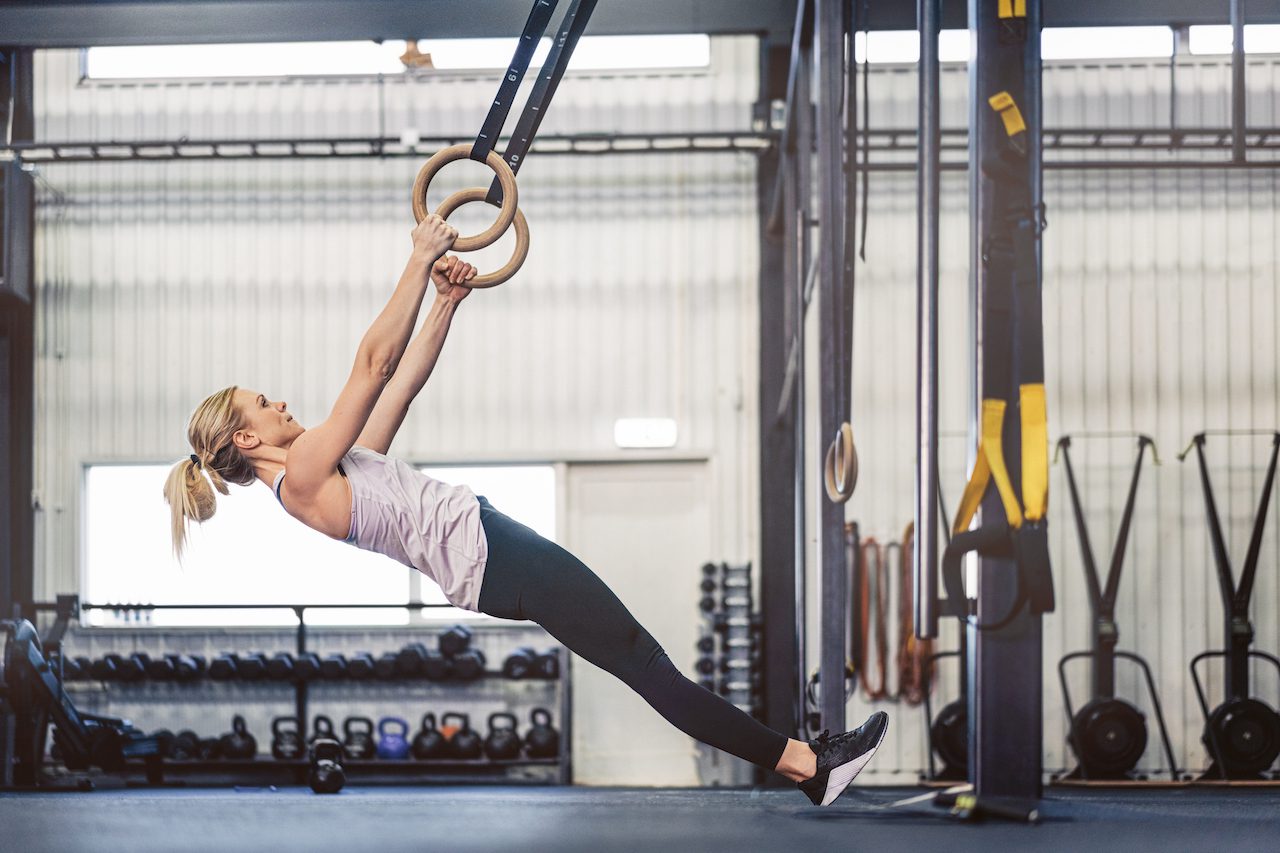 Sporty woman using gymnastic rings/ Sporty women in a gym