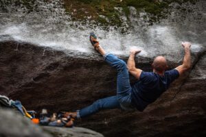 Male boulder traverses rock in La Sportiva Pythons